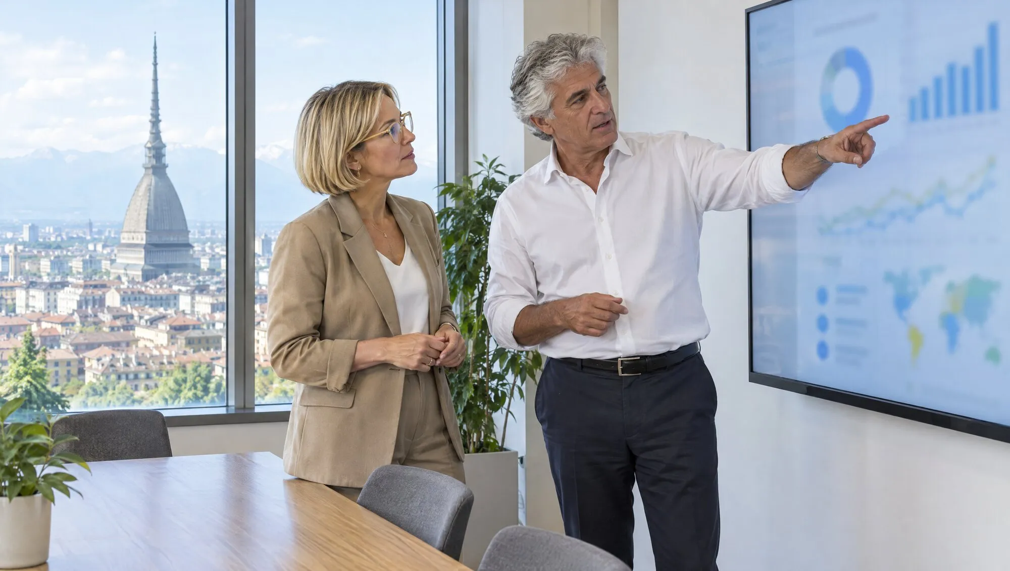Schermo con grafici e due persone che discutono indicando i dati