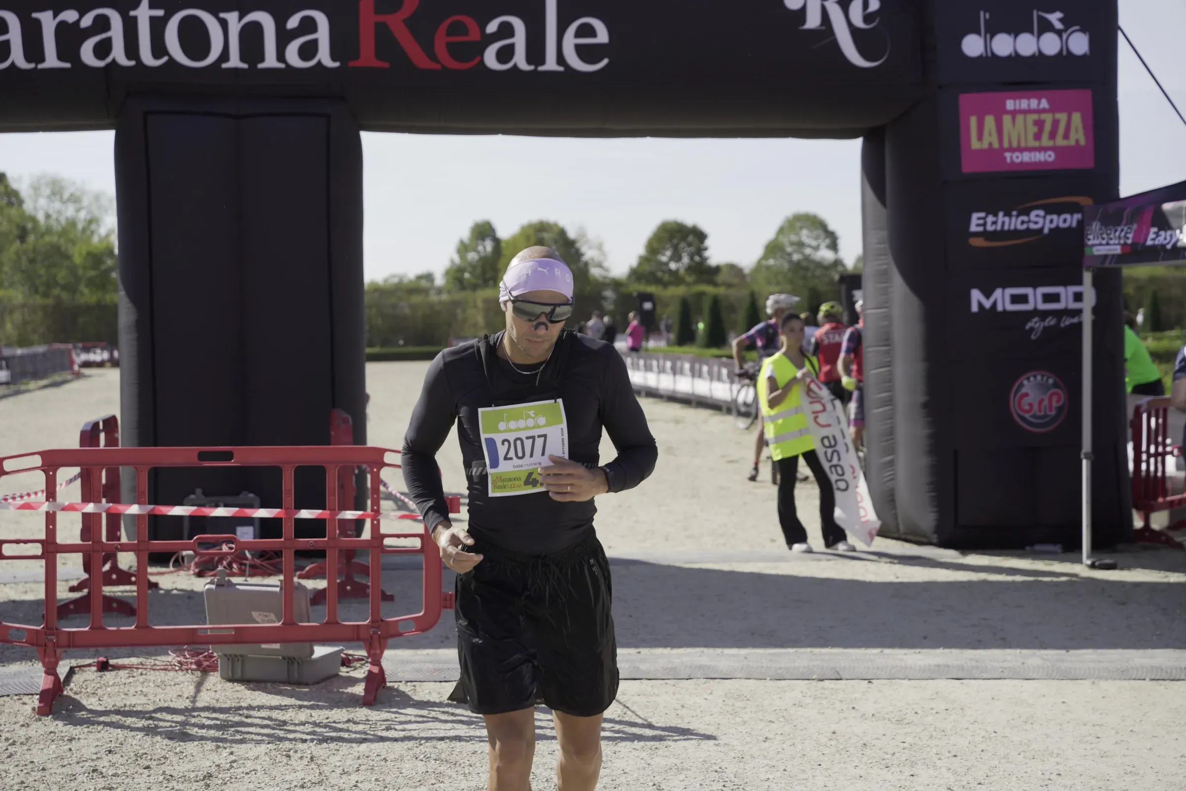 Un maratoneta in nero ferma il cronometro appena passato sotto l'arco della Maratona Reale