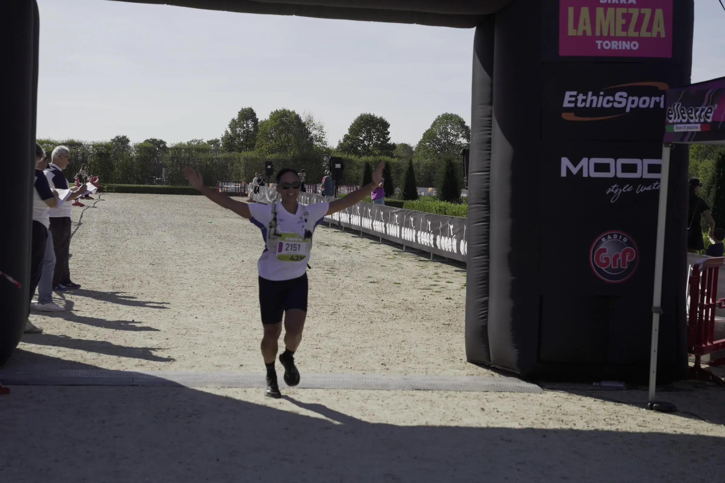 Una maratoneta arriva a braccia aperte sotto l'arco della Maratona Reale