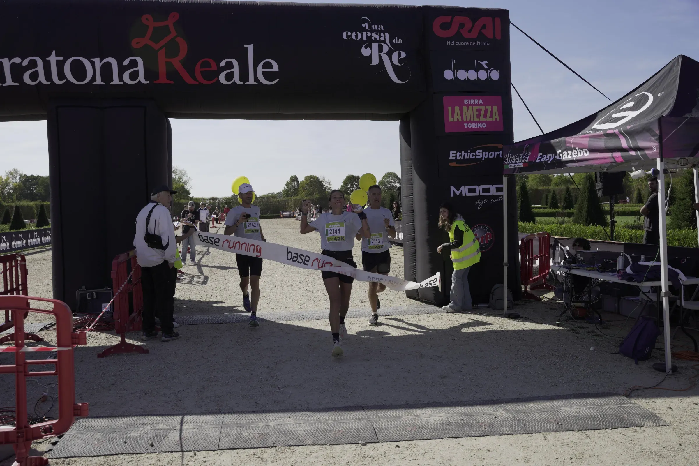 La maratoneta 2144 arriva al traguardo della Maratona Reale tra i due pacer con i palloncini gialli