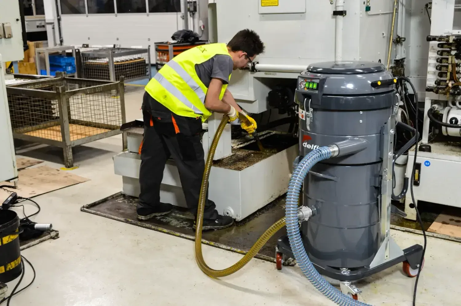 Un operatore aspira trucioli e liquido refrigerante da una macchina CNC con un aspiratore Delfin