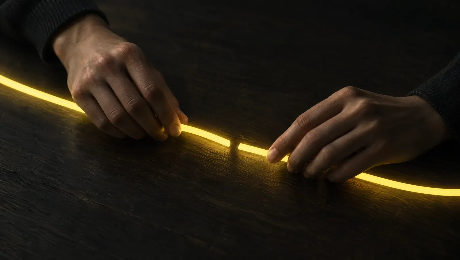 Two hands joining the pieces of a broken luminous path on a dark table, a symbolic image of conversions reconnected to clicks