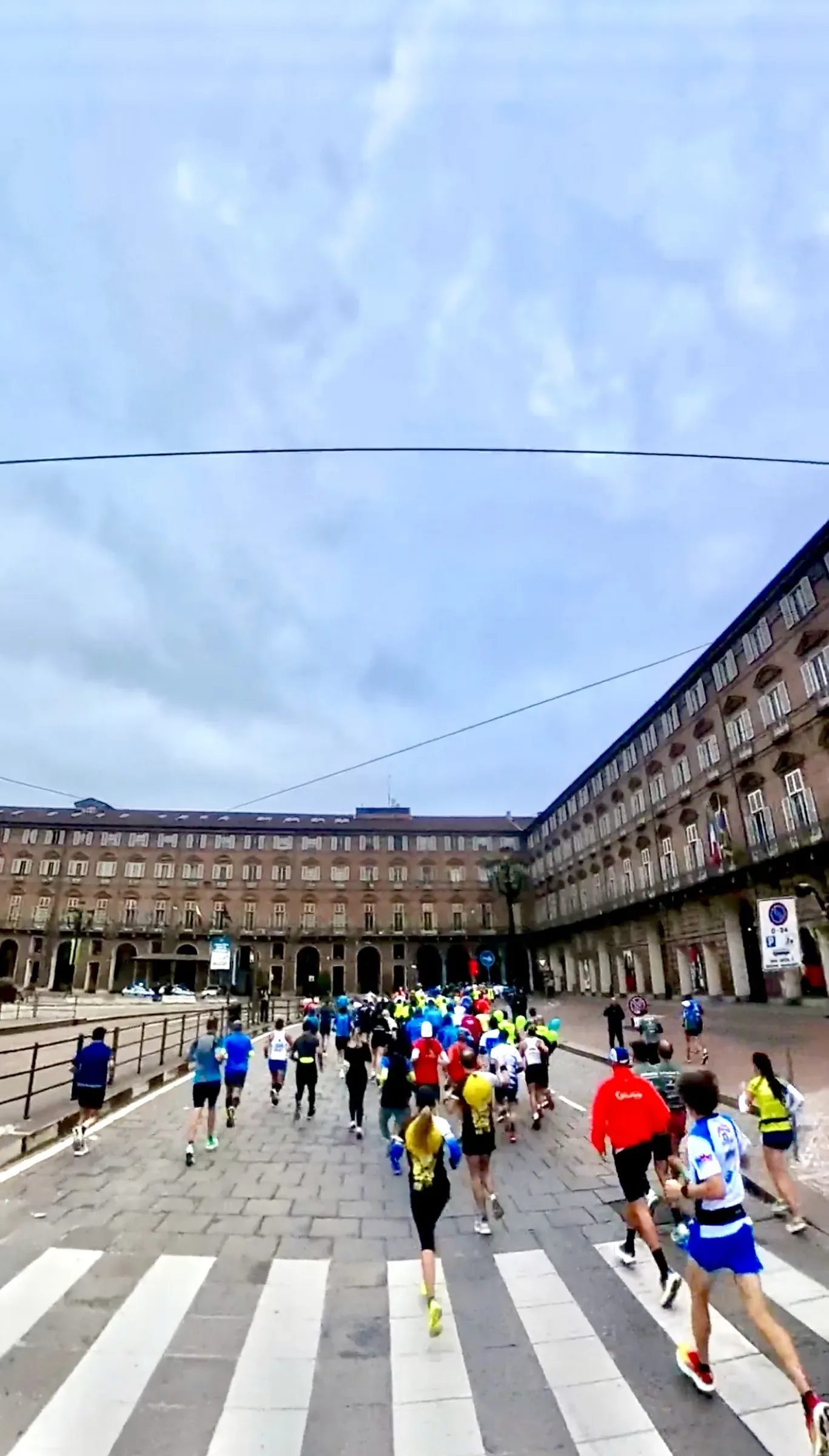 Il gruppo dei runner attraversa piazza Castello a Torino, visto da dietro