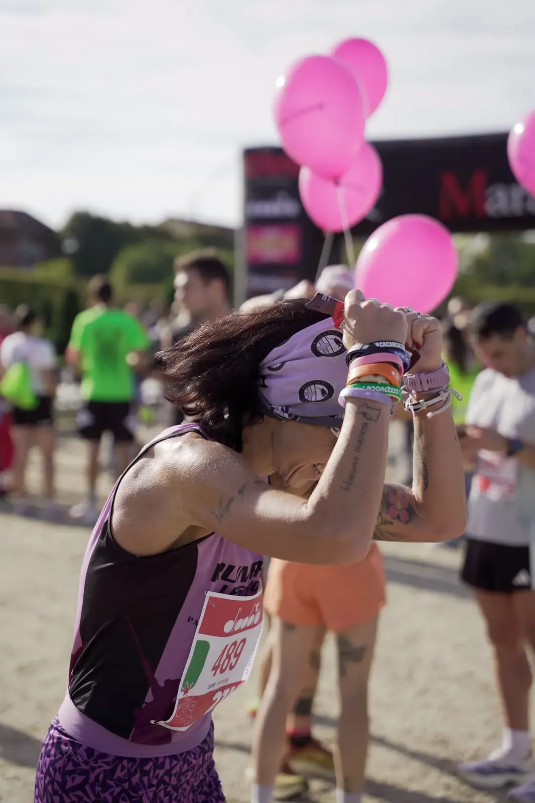 Una runner emozionata appena dopo l'arrivo, con le mani sulla testa e i palloncini rosa alle spalle