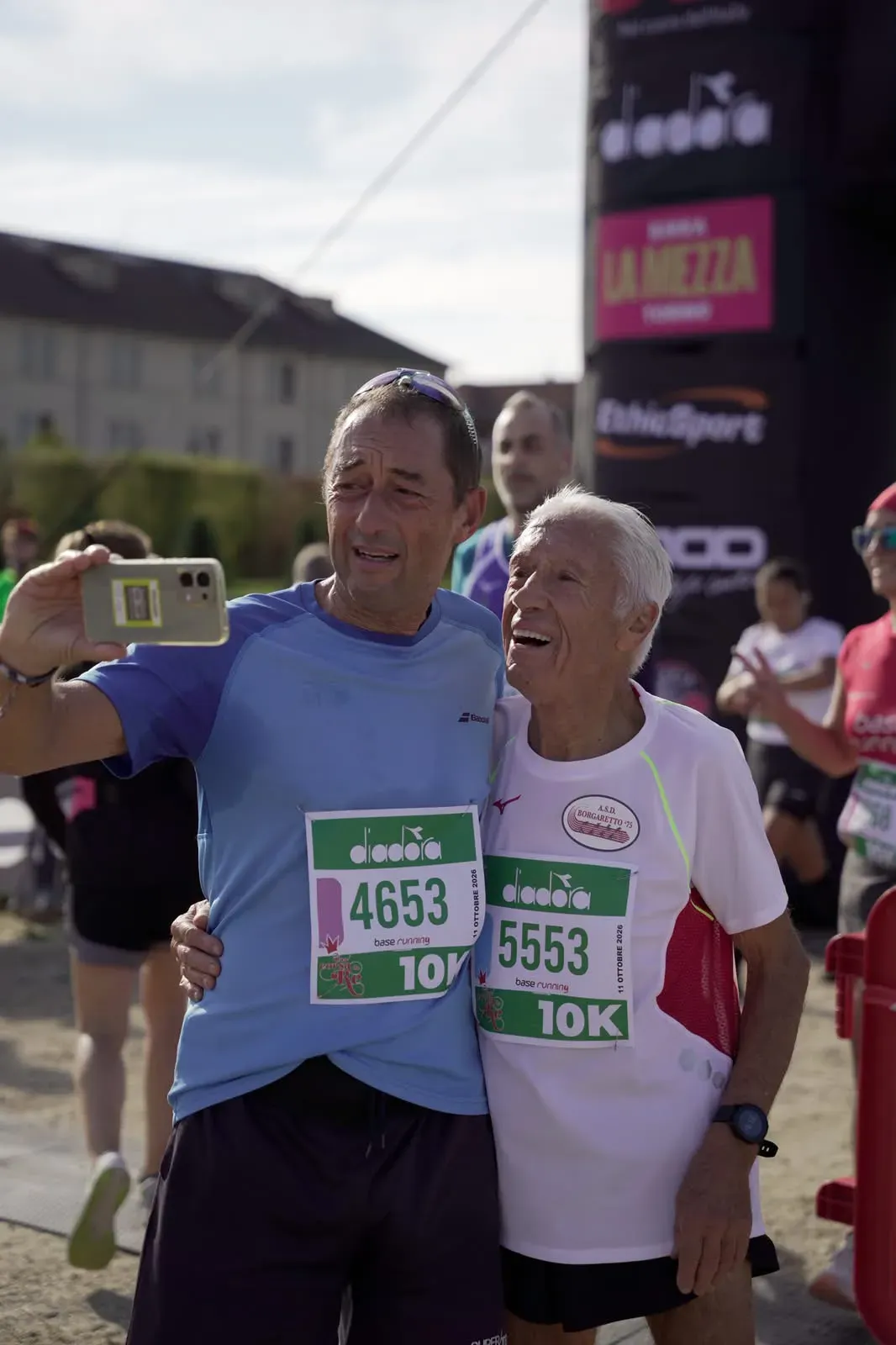 Due runner della 10 km si fanno un selfie dopo il traguardo, uno dei due è un signore anziano sorridente