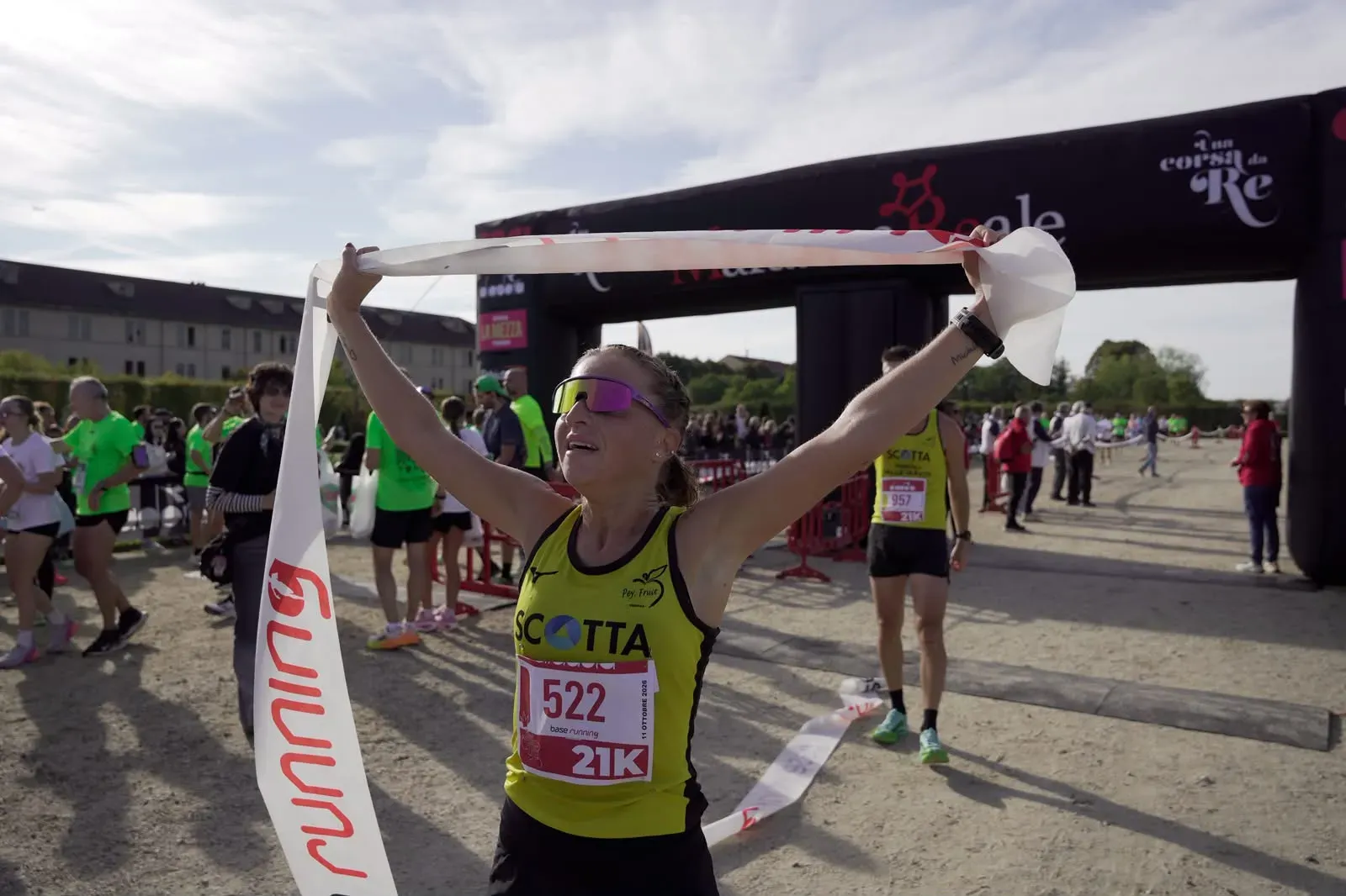Un'atleta della 21 km alza il nastro del traguardo sotto l'arco di Una Corsa da Re