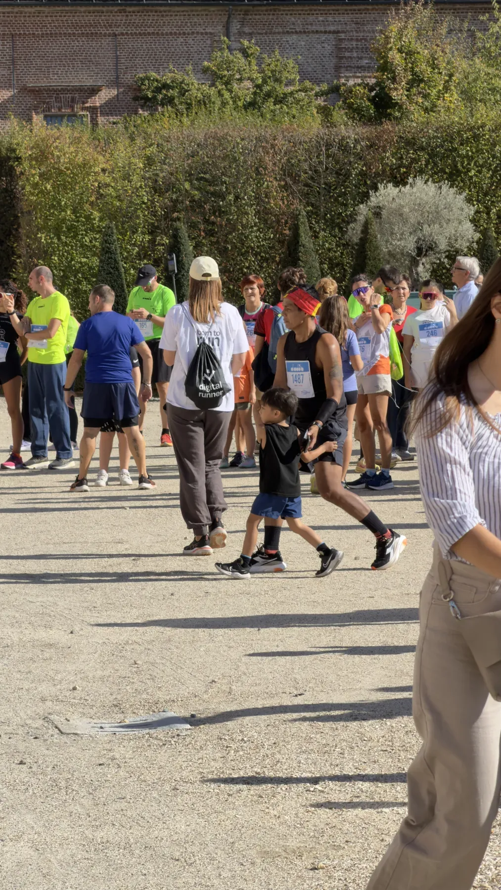 Una persona di Digital Runner di spalle, con la sacca Digital Runner e la maglia born to run, tra i runner con il pettorale nei Giardini della Reggia